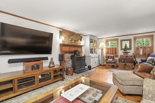 living area with ornamental molding, a wood stove, and light wood finished floors