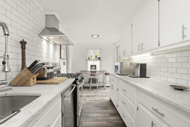 kitchen featuring wall chimney range hood, appliances with stainless steel finishes, dark wood finished floors, and tasteful backsplash