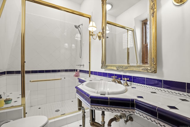 bathroom with a sink, toilet, a shower stall, and tile patterned flooring