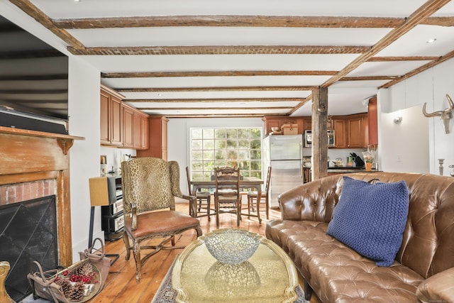 living room featuring wood finished floors, beam ceiling, and a fireplace