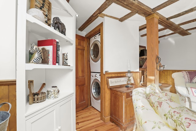 laundry room featuring estacked washer and dryer, light wood finished floors, and wainscoting