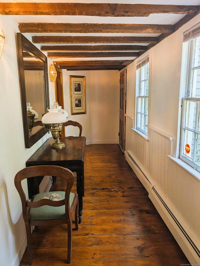 hallway featuring a baseboard heating unit, beamed ceiling, plenty of natural light, dark wood-style floors, and a wainscoted wall