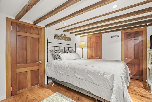bedroom featuring light wood finished floors, beamed ceiling, and recessed lighting