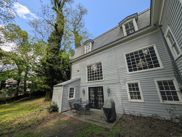 rear view of property featuring french doors, mansard roof, a patio, and a shingled roof