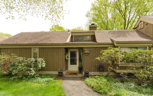 property entrance with a chimney and roof with shingles