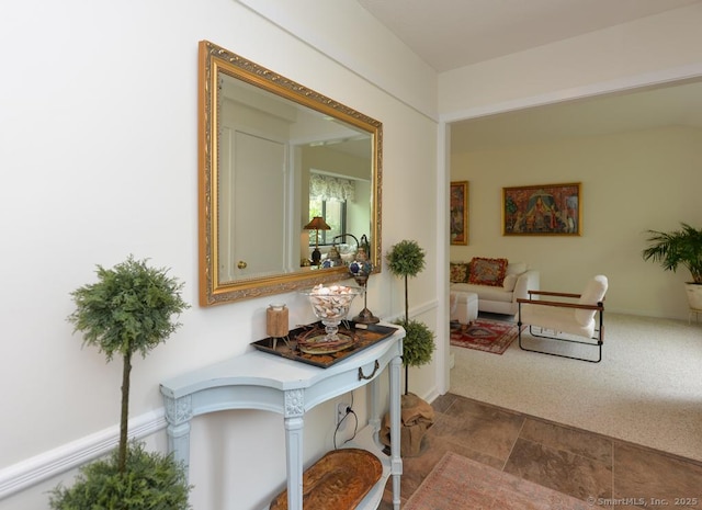 hallway featuring dark stone finish floors and dark colored carpet