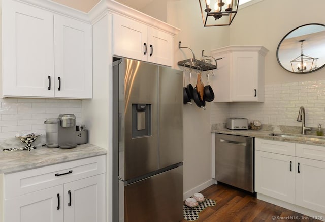 kitchen with stainless steel appliances, a sink, a chandelier, and tasteful backsplash