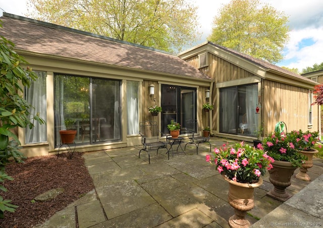 back of house featuring a patio area and roof with shingles