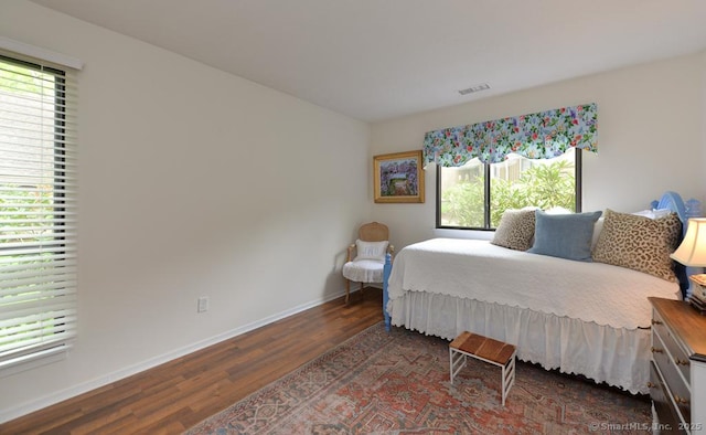 bedroom with wood finished floors, multiple windows, and baseboards
