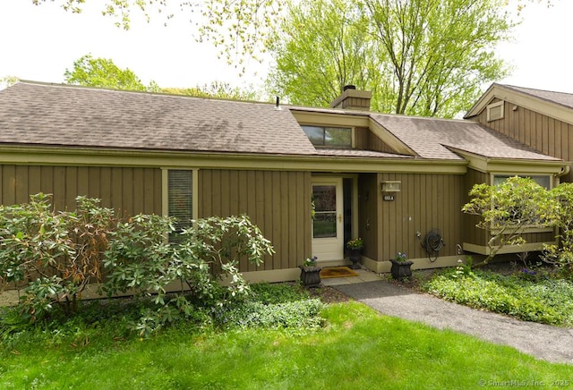 view of exterior entry with a chimney and a shingled roof