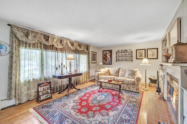 26 Williams Rd, Cheshire, CT 06410 - living room with a textured ceiling, a tile fireplace, light wood-type flooring, and a baseboard radiator