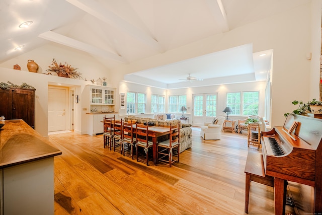 dining area featuring a ceiling fan, light wood-type flooring, beamed ceiling, and high vaulted ceiling