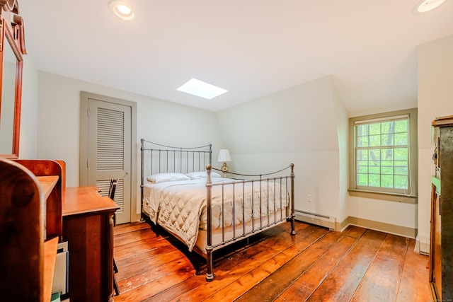 bedroom with baseboard heating, a skylight, light wood-style floors, and recessed lighting