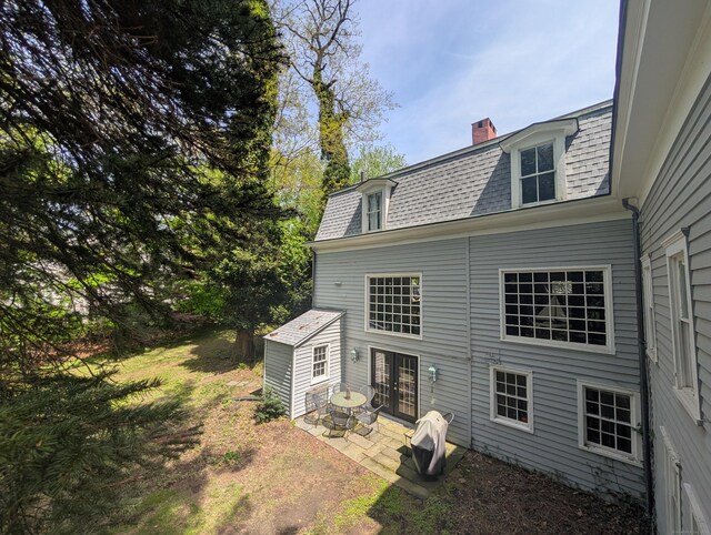 47 Hollow Tree Ridge Rd, Darien, CT 06820 - rear view of property with a patio area, a chimney, mansard roof, and a shingled roof