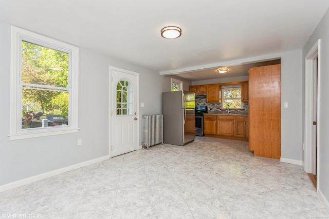 70 Maple St, Meriden, CT 06451 - kitchen featuring radiator, appliances with stainless steel finishes, brown cabinets, baseboards, and decorative backsplash