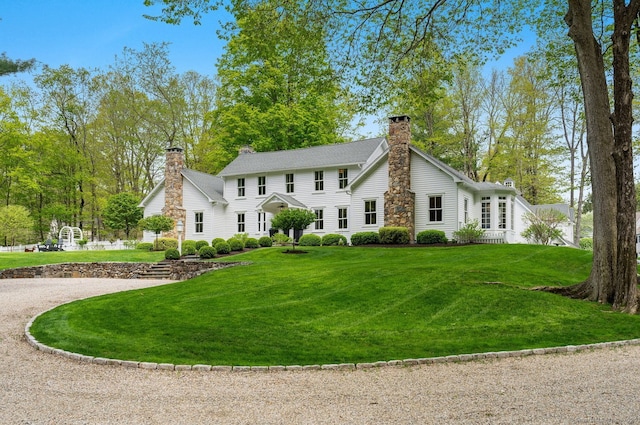rear view of property featuring a chimney and a yard