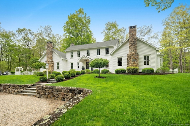 rear view of property with a chimney and a lawn