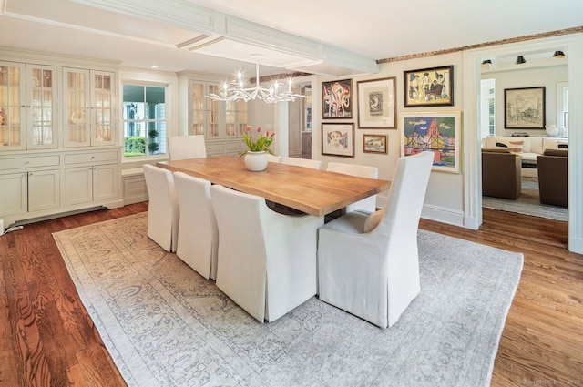 dining space with a chandelier, wood finished floors, and beam ceiling