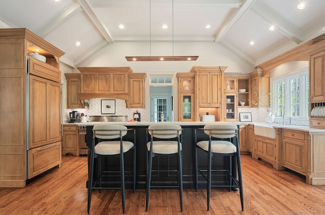 kitchen featuring open shelves, paneled refrigerator, a kitchen island, light countertops, and a breakfast bar