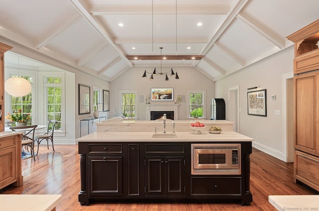 kitchen featuring stainless steel microwave, a sink, open floor plan, baseboards, and a fireplace