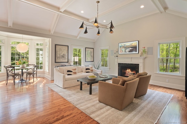 living room with a warm lit fireplace, healthy amount of natural light, beamed ceiling, baseboards, and recessed lighting