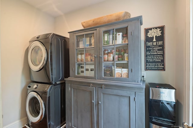 clothes washing area featuring stacked washer / drying machine and baseboards