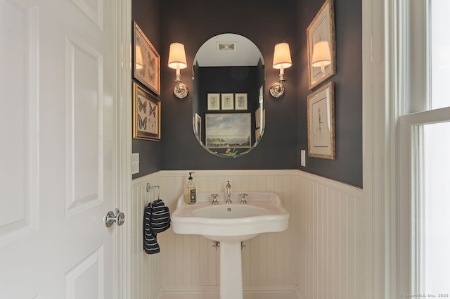 bathroom with a decorative wall and wainscoting