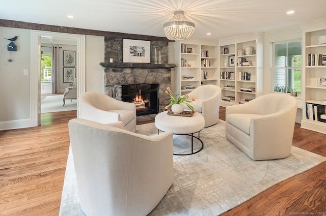 living room with a stone fireplace, wood finished floors, baseboards, a chandelier, and recessed lighting
