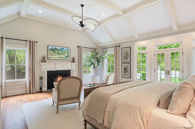 bedroom featuring access to exterior, a lit fireplace, light wood-style flooring, and multiple windows