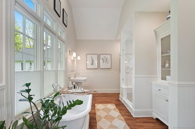 full bath featuring a wainscoted wall, wood finished floors, a shower stall, and a soaking tub
