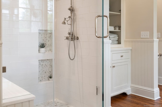 full bathroom featuring a shower stall, wood finished floors, and a wainscoted wall