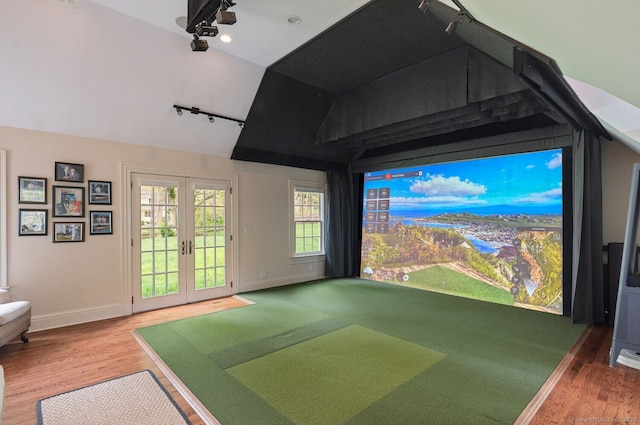 rec room featuring rail lighting, golf simulator, wood finished floors, vaulted ceiling, and baseboards