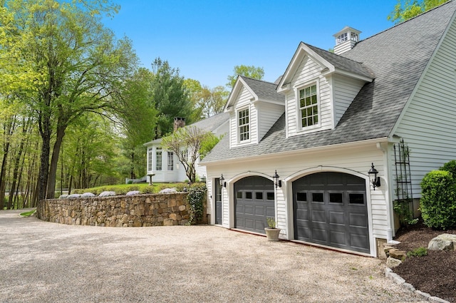 view of side of home with a shingled roof, driveway, and a garage