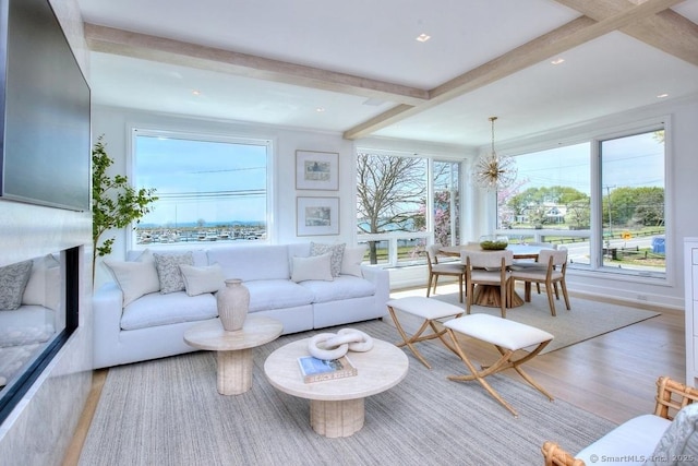 living area featuring beamed ceiling, wood finished floors, and a chandelier