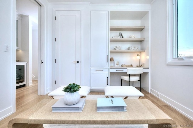 home office with built in study area, light wood finished floors, and baseboards