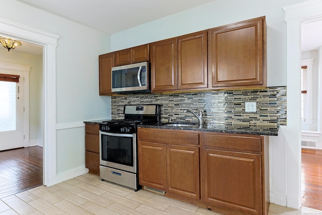 262 Blohm St, West Haven, CT 06516 - kitchen featuring stainless steel appliances, a sink, dark stone counters, light wood finished floors, and backsplash