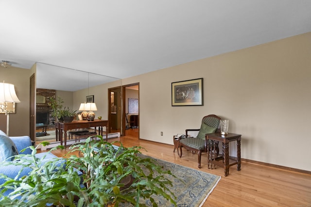 living room with light wood-style floors, a fireplace, baseboards, and baseboard heating