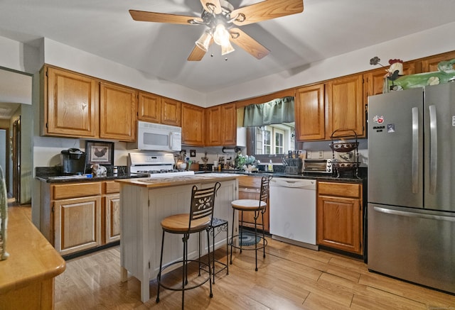 kitchen featuring white appliances, brown cabinets, light wood-style floors, and ceiling fan