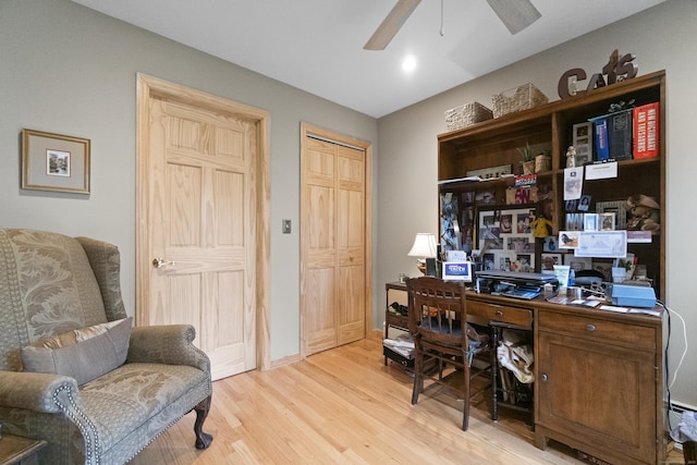 office featuring a ceiling fan, light wood-style floors, and baseboards