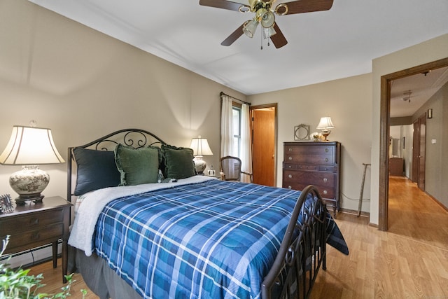 bedroom with a baseboard radiator, light wood-type flooring, a ceiling fan, and baseboards