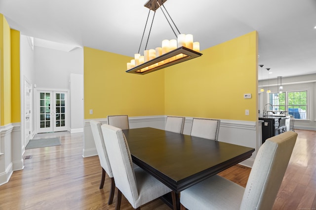 140 Podunk Rd, Guilford, CT 06437 - dining area with a wainscoted wall, light wood-type flooring, french doors, and a chandelier