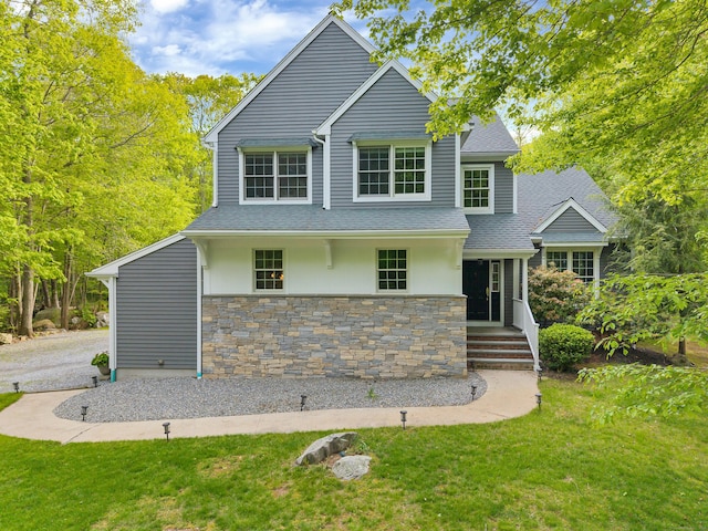 view of front of house featuring stone siding, a front lawn, a shingled roof, and a porch