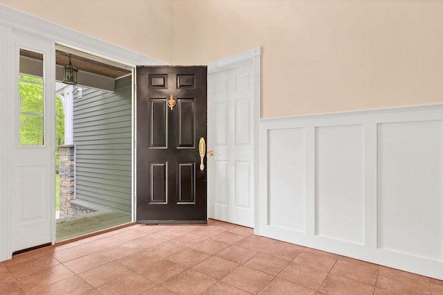entryway with a decorative wall, a wainscoted wall, and light tile patterned flooring