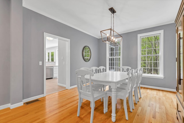 dining room featuring baseboards, a chandelier, ornamental molding, and light wood-style floors