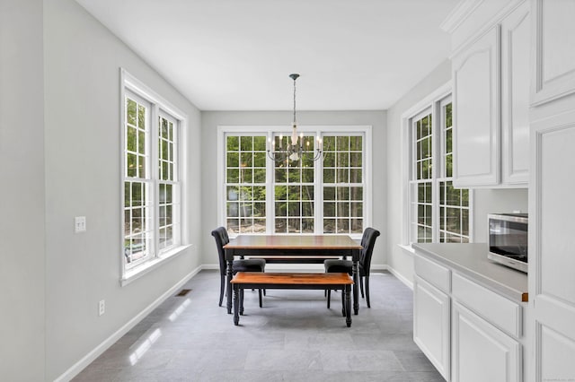 dining space with baseboards, plenty of natural light, and a chandelier