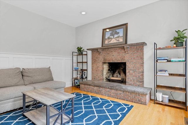 living area featuring wood finished floors, a fireplace, a wainscoted wall, a decorative wall, and recessed lighting