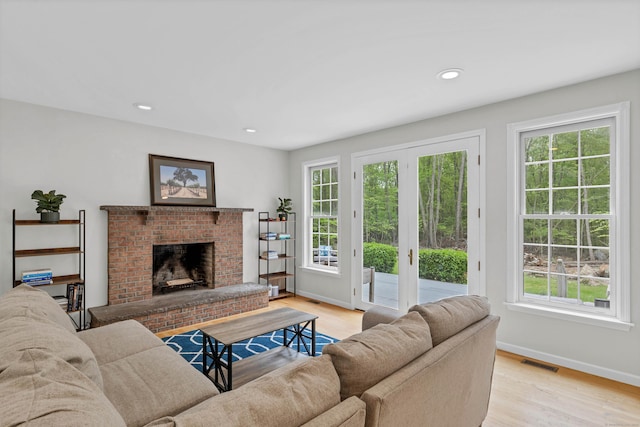 living area featuring a brick fireplace, light wood-style flooring, baseboards, and recessed lighting