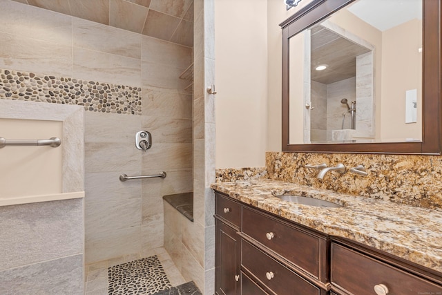 full bath with a tile shower and vanity