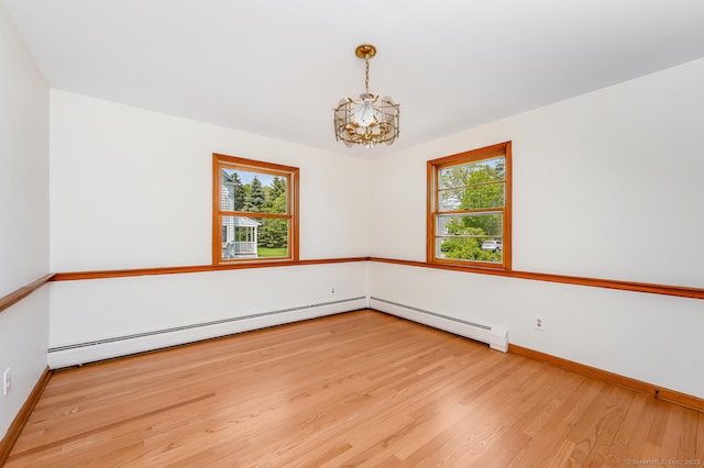 spare room with a chandelier, wood finished floors, baseboards, and a baseboard heating unit