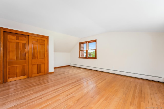 bonus room with a baseboard radiator, light wood-style flooring, lofted ceiling, and baseboards